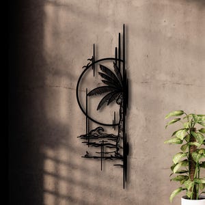 May include: Black metal wall art depicting a tropical scene. A palm tree, waves, and a sun are featured within a circular frame. Vertical lines and a bird silhouette add to the design. The artwork is mounted on a textured gray wall.