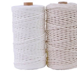 Peut inclure: Deux bobines de corde en coton naturel, une blanche et une beige. La corde est enroulée fermement autour des bobines.