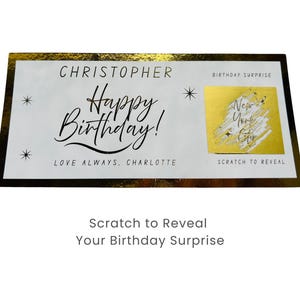 May include: A rectangular birthday card with a gold border and accents. The card reads "CHRISTOPHER Happy Birthday! LOVE ALWAYS, CHARLOTTE." A gold scratch-off area reveals "New York City." The text "Scratch to Reveal Your Birthday Surprise" is below.
