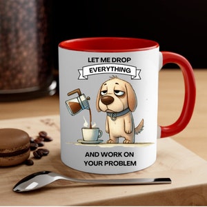 May include: White ceramic coffee mug with a red rim and handle. The mug features a cartoon dog pouring coffee from a coffee pot into a cup. The text on the mug reads "Let me drop everything and work on your problem."