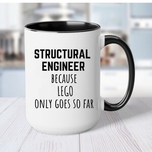 May include: White ceramic coffee mug with a black rim and handle. The mug has black text that reads "Structural Engineer because Lego only goes so far."