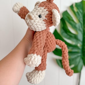 Peut inclure: Un jouet singe crochet&eacute; &agrave; la main, dans les tons marron et cr&egrave;me. Le singe a un aspect textur&eacute; et moelleux avec une longue queue et les bras tendus. Le visage du jouet pr&eacute;sente de petits yeux noirs et un nez beige. Les oreilles et les pieds sont de couleur cr&egrave;me.