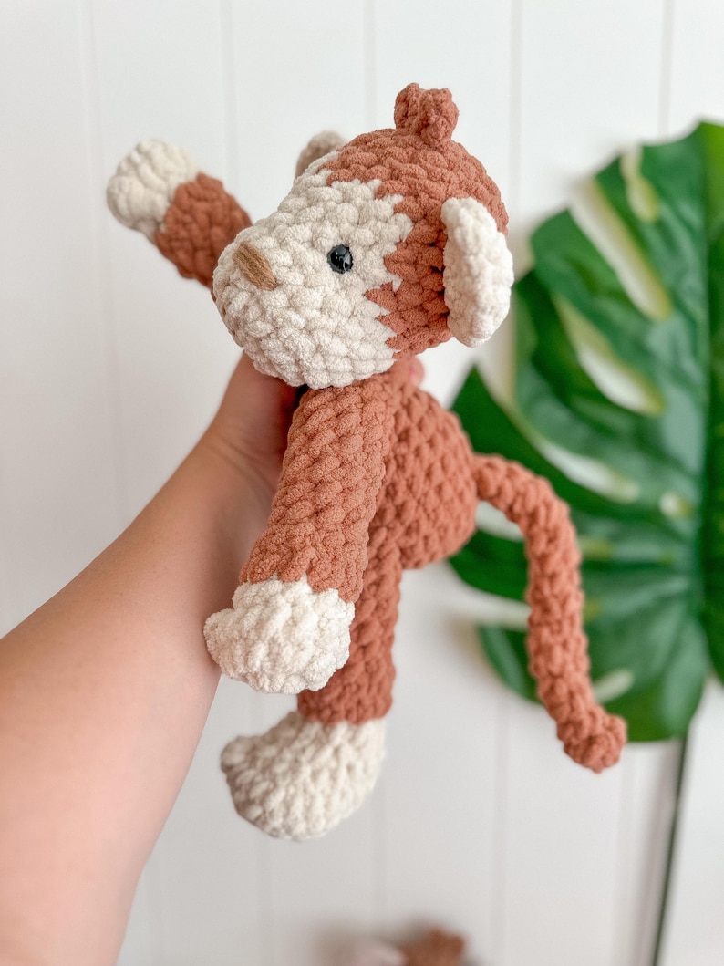 Peut inclure: Un jouet singe crochet&eacute; &agrave; la main, dans les tons marron et cr&egrave;me. Le singe a un aspect textur&eacute; et moelleux avec une longue queue et les bras tendus. Le visage du jouet pr&eacute;sente de petits yeux noirs et un nez beige. Les oreilles et les pieds sont de couleur cr&egrave;me.
