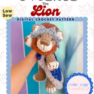 Könnte beinhalten: Ein gehäkeltes Löwenplüschtier namens Archie, das eine Krone und einen blauen Umhang trägt. Das Bild enthält den Text "Archie The Lion DIGITAL CROCHET PATTERN" und "Low Sew". Das Plüschtier ist Teil der "TIMELESS PLUSHIE COLLECTION".