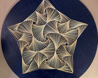 May include: A wooden artwork with a five-pointed star design. The star is made from thin, light-coloured wooden strips arranged in a spiral pattern against a dark blue circular background. The artwork is mounted on a round wooden base.
