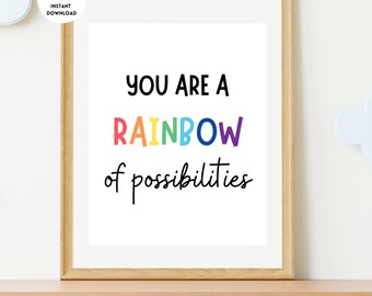 May include: A framed print with the words "YOU ARE A RAINBOW of possibilities" in black and rainbow-colored text. The print is in a light wood frame and sits on a wooden shelf. A white cloud-shaped decoration is visible.