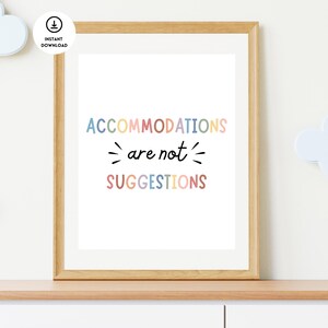 May include: A framed print with the text "ACCOMMODATIONS are not SUGGESTIONS" in a rainbow of colors. The print is in a light wood frame and is hanging on a wall.
