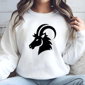 May include: White sweatshirt with a black silhouette of a goat's head, representing the zodiac sign Capricorn.