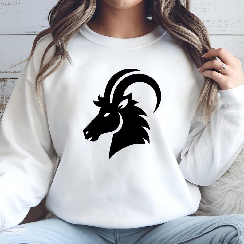 May include: White sweatshirt with a black silhouette of a goat's head, representing the zodiac sign Capricorn.