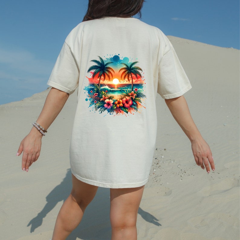 Pu&ograve; includere: Una maglietta bianca con una stampa grafica colorata di una scena di tramonto tropicale con palme, fiori e una spiaggia.