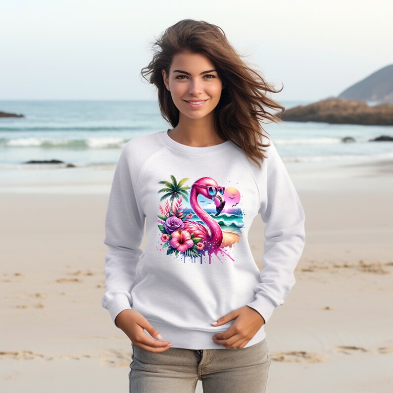 May include: White sweatshirt with a pink flamingo wearing sunglasses and a tropical beach scene with palm trees, flowers, and ocean waves.
