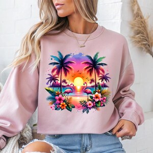 May include: Pink sweatshirt with a colorful graphic print of palm trees, flamingos, and a sunset over the ocean. The graphic is surrounded by tropical flowers.