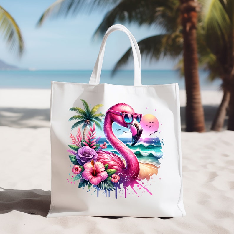 May include: White tote bag with a pink flamingo wearing sunglasses and a tropical floral design. The flamingo is standing in front of a beach scene with waves and a sunset.