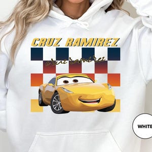 A white hoodie with a graphic of a yellow car and the text "CRUZ RAMIREZ" printed on it.
