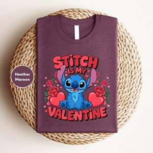 A purple t-shirt with a graphic design featuring a blue cartoon character and text that says "Stitch is my Valentine".