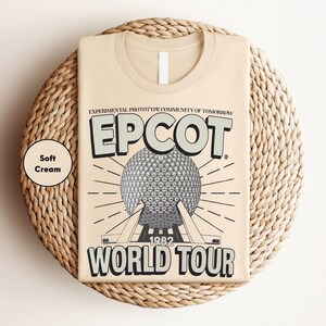 a beige t-shirt with a graphic design depicting the EPCOT World Tour from 1982.