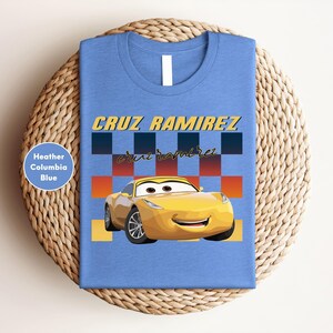 A blue t-shirt with a yellow car and the name "CRUZ RAMIREZ" printed on it, along with a checkered pattern.