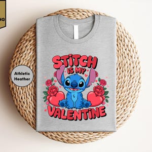 A gray t-shirt with a graphic design featuring a blue cartoon character and text that says "Stitch is my Valentine".