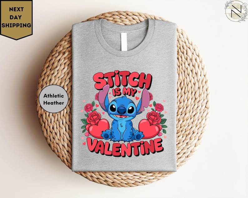 A gray t-shirt with a graphic design featuring a blue cartoon character and text that says "Stitch is my Valentine".