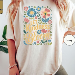 a woman wearing a t - shirt that says let kindness bloom