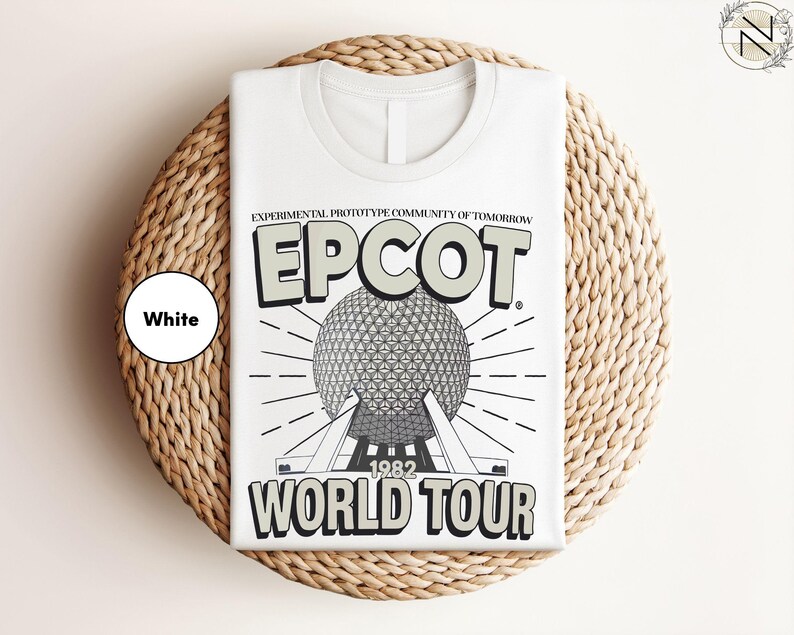 A white t-shirt with a graphic design featuring the EPCOT World Tour logo and a large globe, placed on a woven placemat.