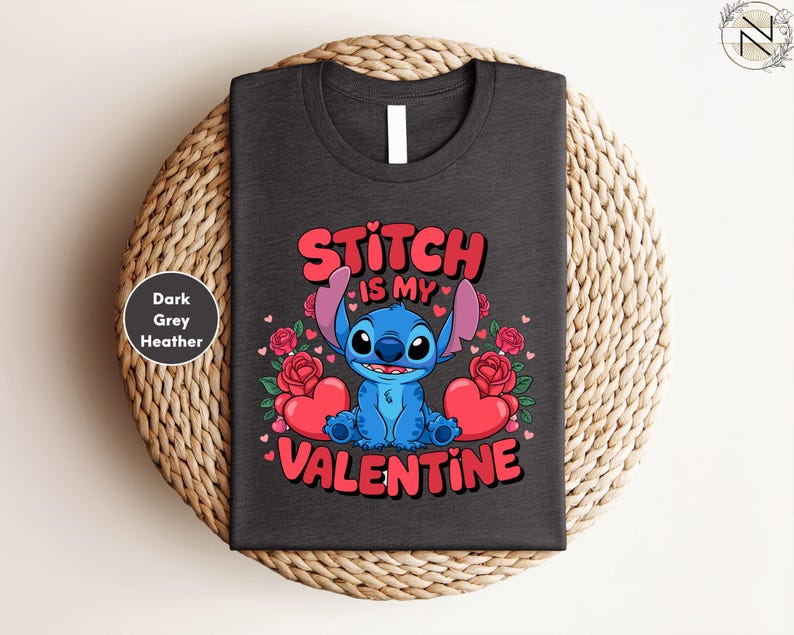 A black t-shirt with a graphic design featuring a blue character, likely Stitch, surrounded by hearts and roses, with the text "Stitch is my Valentine" printed on it.