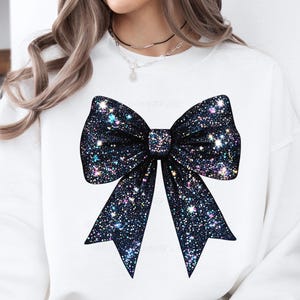 May include: White sweatshirt with a large black sparkly bow on the front.