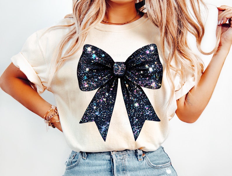 May include: A white t-shirt with a large black glitter bow design. The bow has iridescent glitter accents.