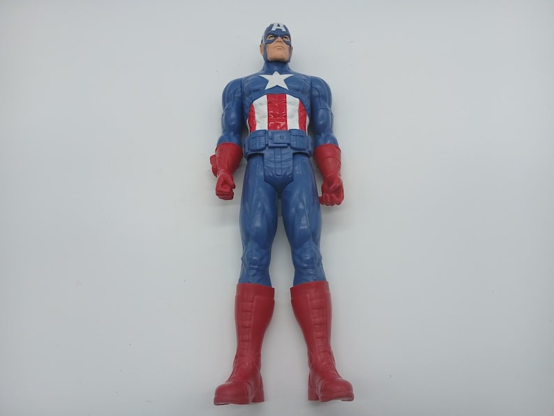 May include: A Captain America action figure. The figure is in a standing pose, wearing a blue and red costume with a white star on the chest. The figure has a blue helmet with a white "A" on the forehead and red gloves and boots.
