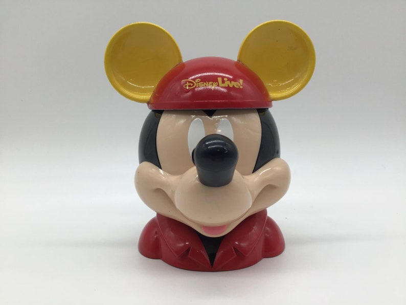 May include: A red and yellow plastic Mickey Mouse head shaped container with the text "Disney Live!" on the hat.