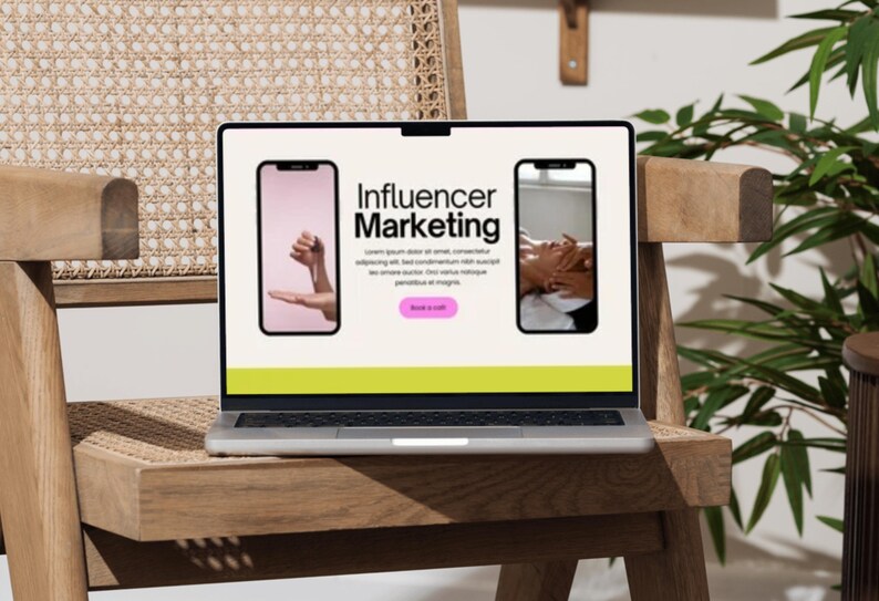 May include: A laptop displaying a webpage about "Influencer Marketing" with two smartphone mockups. The laptop sits on a wooden chair with a woven back. The screen has a light green and cream color scheme.