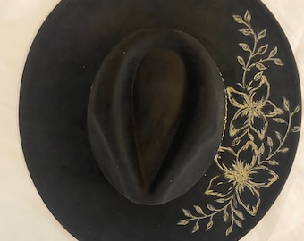 Schwarzer Hut mit eingebrannten metallischen Blüten in Gold