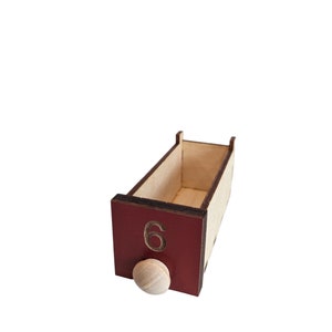 May include: A wooden box with a red front panel and a number "6" printed on it. The box has a small wooden knob on the front.