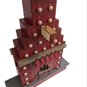 May include: A red wooden Christmas advent calendar shaped like a chimney with 25 drawers. The drawers are numbered 1 through 25. The calendar has a gray roof and a gray base. The text "STURM FAMILY CHRISTMAS" is printed on the base.