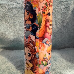 May include: A white ceramic mug with a black handle and the text "But First, Coffee" in a bold, black font. The mug is set against a blurred background, suggesting a cosy setting.