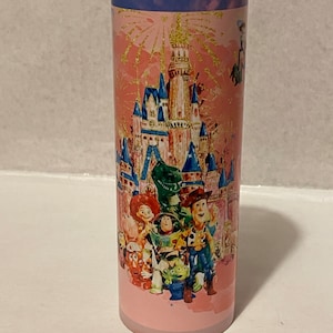 May include: Pink stainless steel tumbler with a colorful image of the Disney castle and characters from the Toy Story franchise. The characters include Woody, Buzz Lightyear, Jessie, Rex, and Mr. Potato Head.