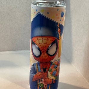 Pode incluir: Um copo de a&ccedil;o inoxid&aacute;vel com um tema de gradua&ccedil;&atilde;o que apresenta uma imagem de desenho animado do Homem-Aranha usando uma touca e uma beca de gradua&ccedil;&atilde;o azuis, segurando um buqu&ecirc; de flores. O fundo &eacute; branco com cora&ccedil;&otilde;es e estrelas azuis, rosa e amarelos.