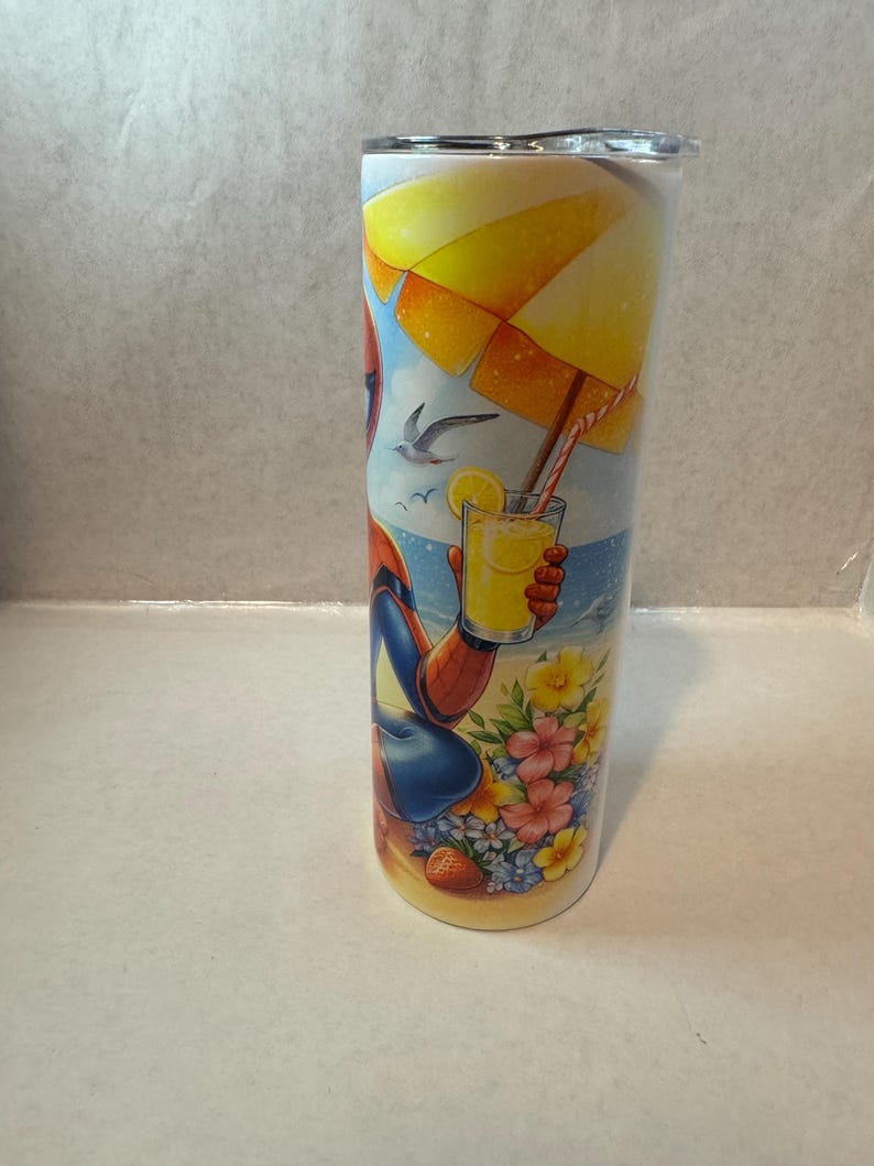 May include: A stainless steel tumbler with a colorful design featuring a cartoon superhero relaxing on a beach with a glass of lemonade under an umbrella.
