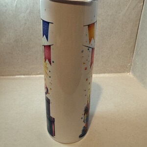 Może przedstawiać: Biały kubek ze stali nierdzewnej z wzorem tortu urodzinowego. Tort jest ozdobiony kolorowymi posypkami, świeczkami i banerem. Kubek idealnie nadaje się do przechowywania gorących lub zimnych napoj&oacute;w.