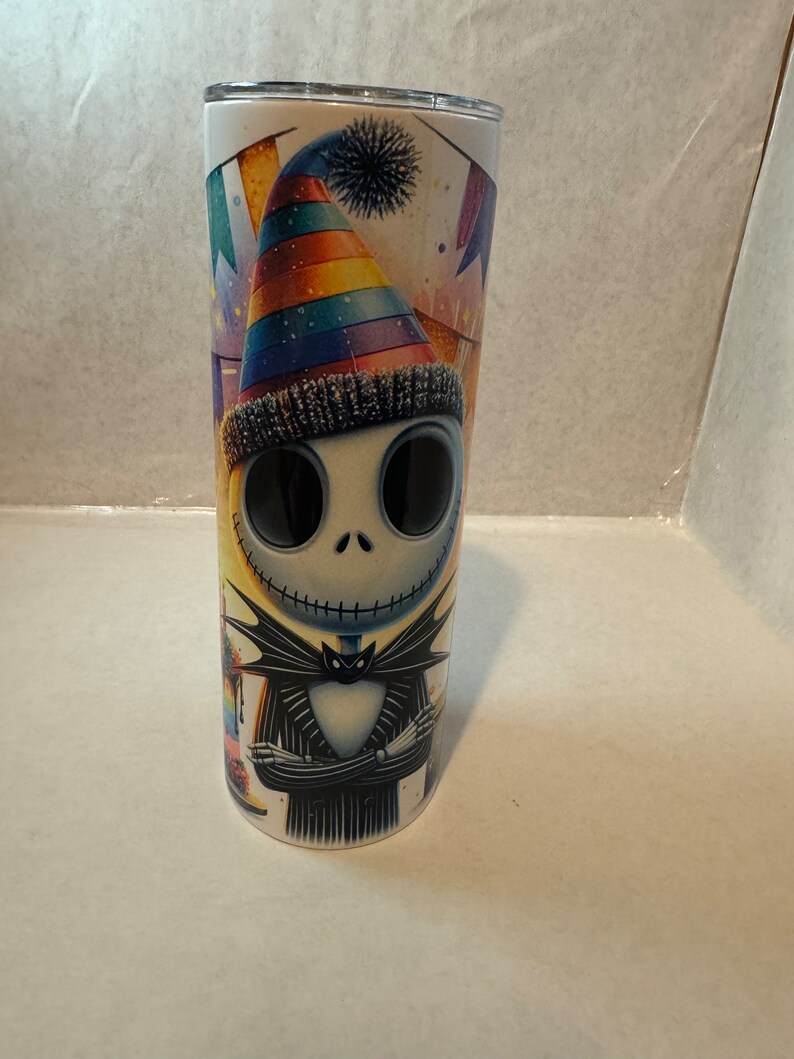 Może przedstawiać: Kubek ze stali nierdzewnej z kolorowym wzorem przedstawiającym postać z kresk&oacute;wki w tęczowym kapeluszu imprezowym. Postać ma na sobie czarno-biały pasiasty garnitur i czarny krawat. Tło to kolorowa scena imprezowa z konfetti i serpentynami.