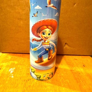 May include: A stainless steel tumbler with a colorful design featuring a cartoon character from the Toy Story franchise. The character is depicted surfing on a wave with a blue sky and seagulls in the background.