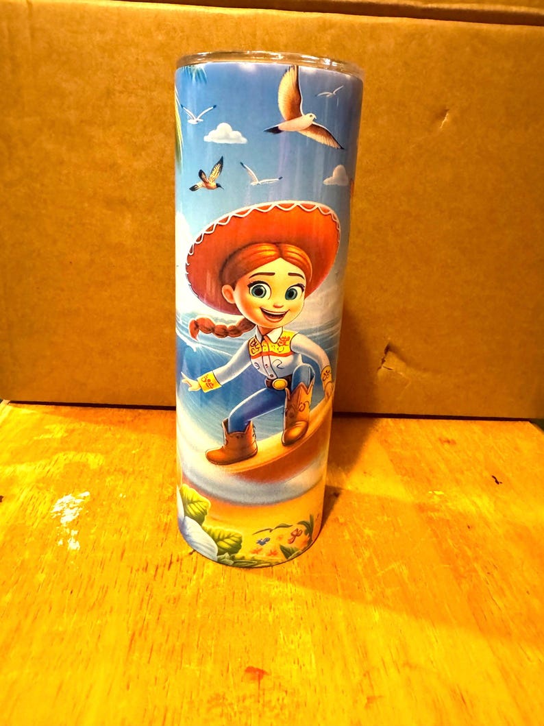 May include: A stainless steel tumbler with a colorful design featuring a cartoon character from the Toy Story franchise. The character is depicted surfing on a wave with a blue sky and seagulls in the background.