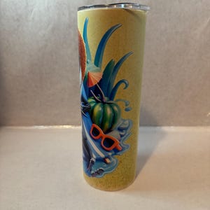 K&ouml;nnte beinhalten: Ein hoher, zylindrischer Becher mit gelbem Hintergrund und einem farbenfrohen tropischen Design. Das Design umfasst einen gr&uuml;nen K&uuml;rbis, eine orangefarbene Sonnenbrille, blaue Bl&auml;tter und einen kleinen orangefarbenen Regenschirm. Der Becher hat einen silbernen Rand und einen transparenten Deckel.