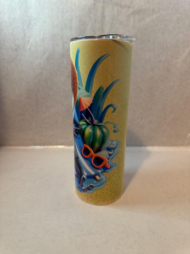 K&ouml;nnte beinhalten: Ein hoher, zylindrischer Becher mit gelbem Hintergrund und einem farbenfrohen tropischen Design. Das Design umfasst einen gr&uuml;nen K&uuml;rbis, eine orangefarbene Sonnenbrille, blaue Bl&auml;tter und einen kleinen orangefarbenen Regenschirm. Der Becher hat einen silbernen Rand und einen transparenten Deckel.