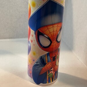 Pode incluir: Um copo de a&ccedil;o inoxid&aacute;vel branco com um design colorido que apresenta uma imagem de desenho animado do Homem-Aranha usando um chap&eacute;u de formatura e uma beca. O design tamb&eacute;m inclui bal&otilde;es coloridos, cora&ccedil;&otilde;es e estrelas.