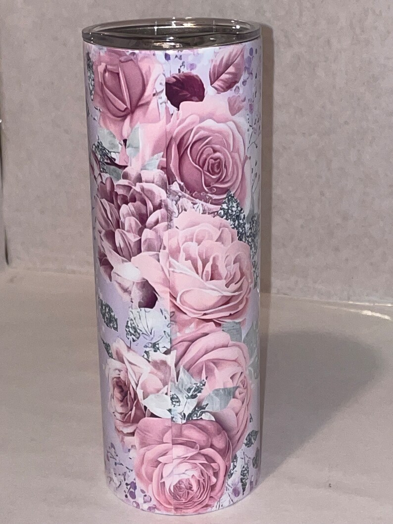 May include: A stainless steel tumbler with a floral design featuring pink roses and leaves on a white background.