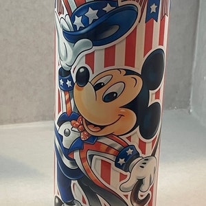 Peut inclure: Un gobelet en acier inoxydable avec un motif patriotique rouge, blanc et bleu repr&eacute;sentant Mickey Mouse habill&eacute; en Oncle Sam. Le gobelet a un couvercle blanc.