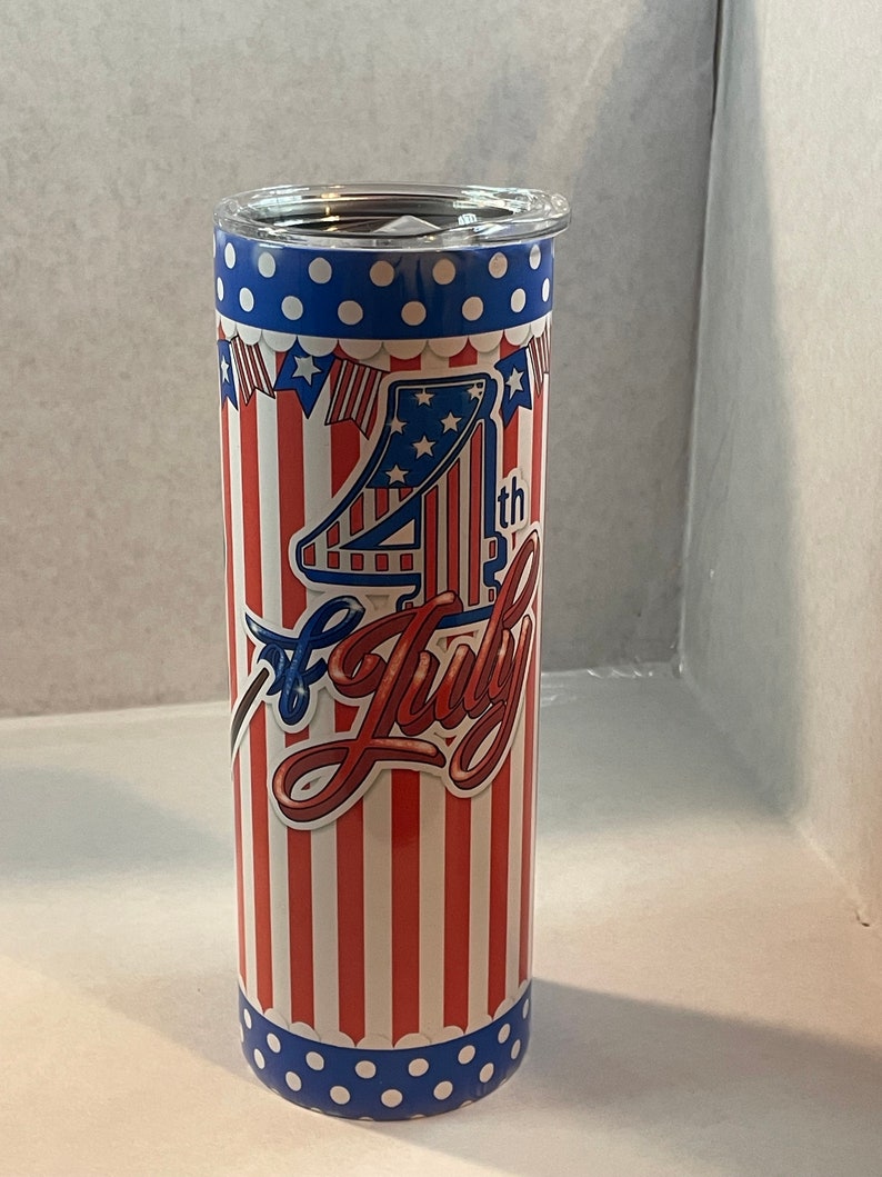 Peut inclure: Un gobelet en acier inoxydable rouge, blanc et bleu avec un motif du 4 juillet. Le gobelet pr&eacute;sente un fond ray&eacute; rouge, blanc et bleu avec un motif d'&eacute;toiles blanches. Le texte "4th of July" est &eacute;crit en blanc, rouge et bleu. Le gobelet a un couvercle bleu avec des pois blancs.
