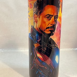 May include: A stainless steel tumbler with a colorful image of Iron Man from the Marvel Cinematic Universe. The image features Iron Man's face and a close-up of his suit.