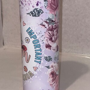 May include: A stainless steel tumbler with a floral design and the text "Important Work" in pink and blue lettering. The tumbler has a white background with a pink and purple floral pattern.
